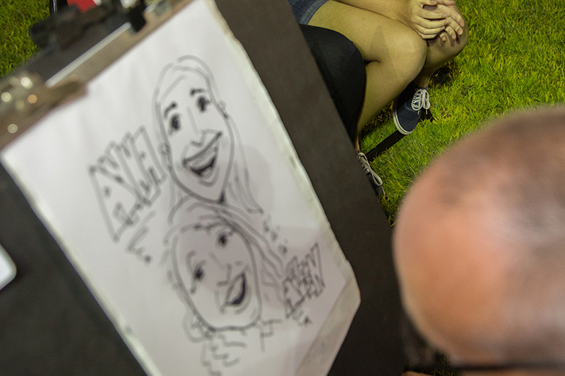 A caricature artist draws a portrait of two female students